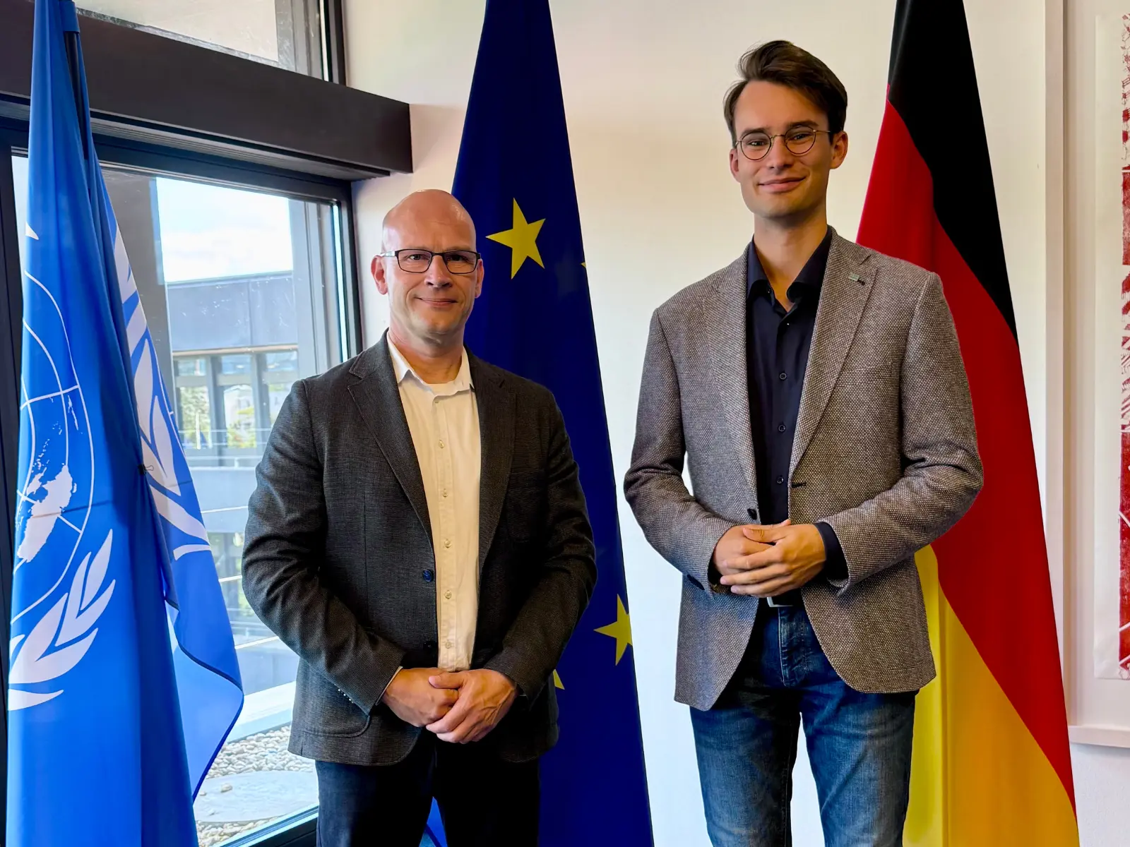 Timm Kloevekorn und Arthur Röben vor der UN-, der Europa- und der Deutschlandflagge
